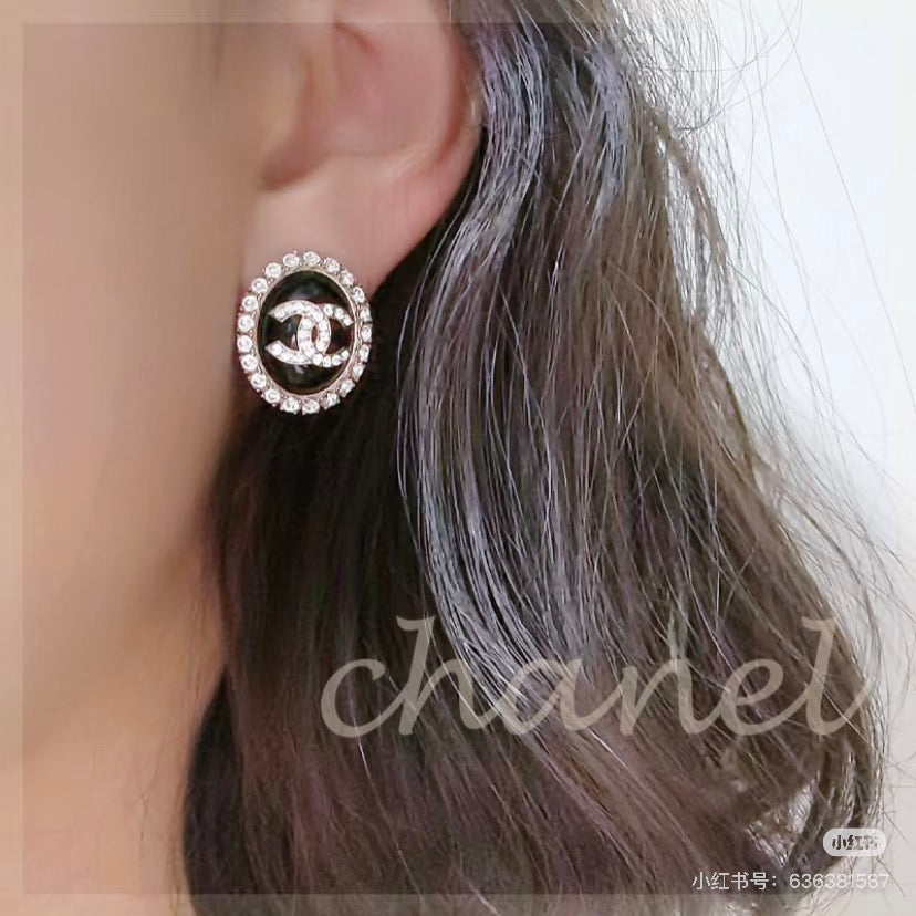 Black enamel CC logo crystal stud earrings on ear, gold-tone post visible