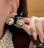 Chanel stud earrings close-up in hand, round silver-tone logo discs