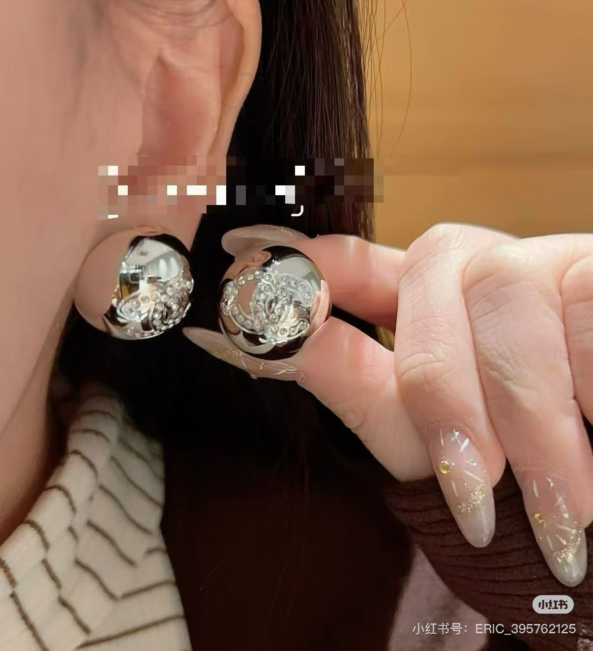 Chanel stud earrings close-up in hand, round silver-tone logo discs