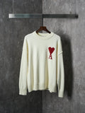 Cream knit sweater with crew neck and red heart-and-A appliqué on the chest