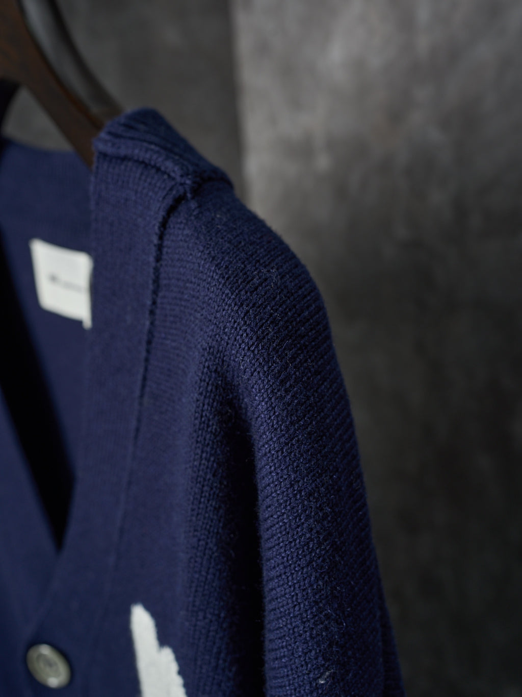 Side view of navy knit cardigan with ribbed shoulder seam and button placket detail