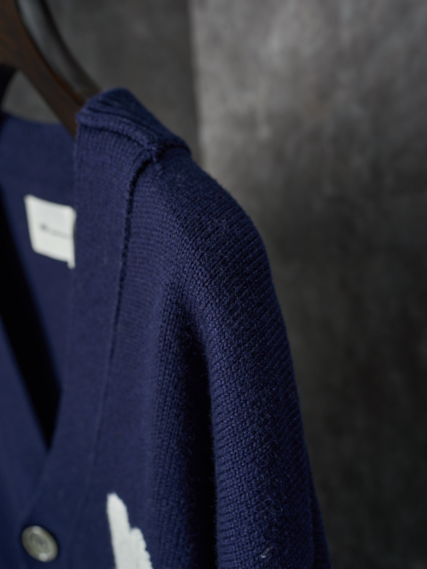 Side view of navy knit cardigan with ribbed shoulder seam and button placket detail