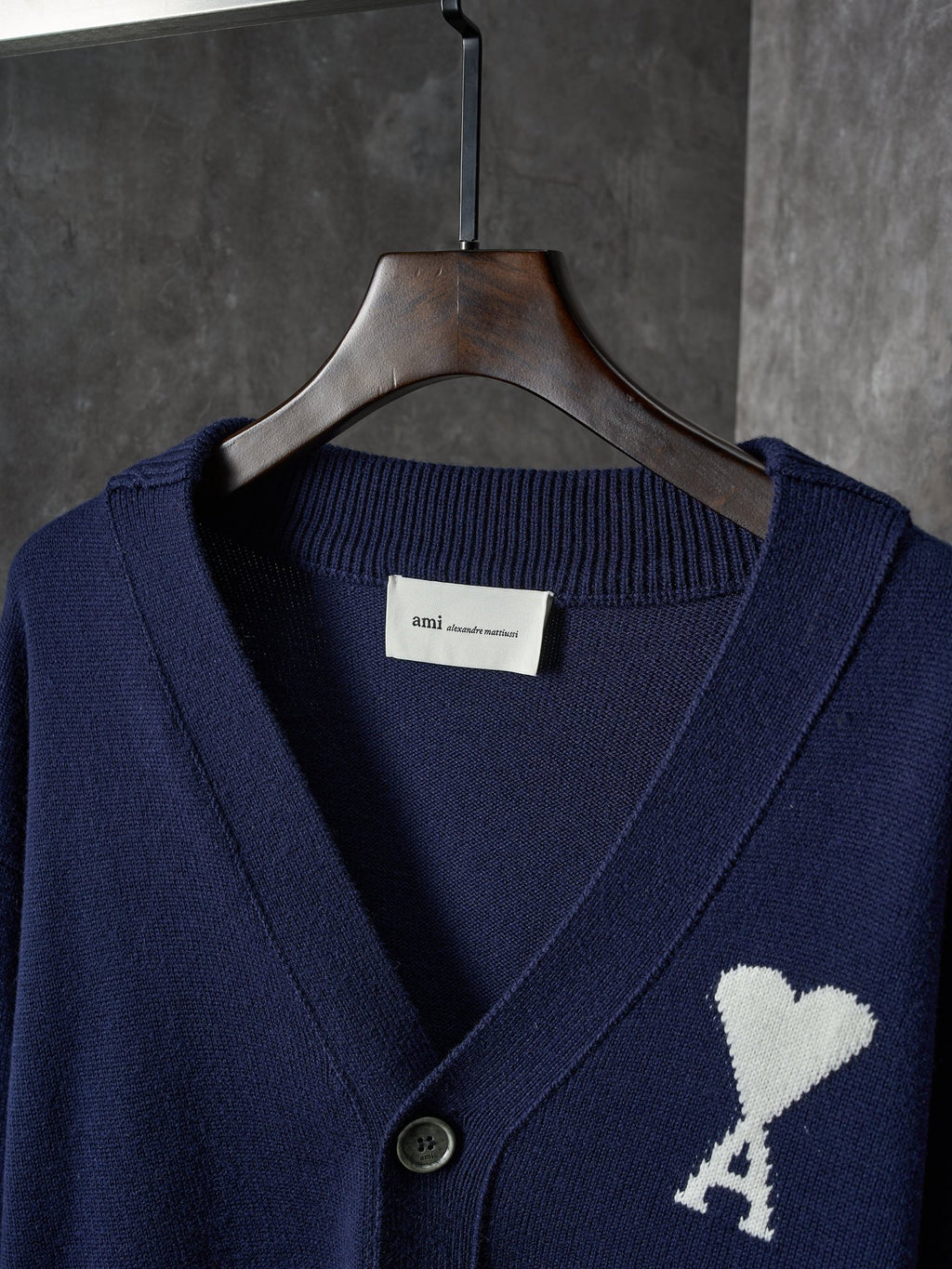 Navy knit cardigan close-up of V-neck, dark buttons, and white heart A emblem