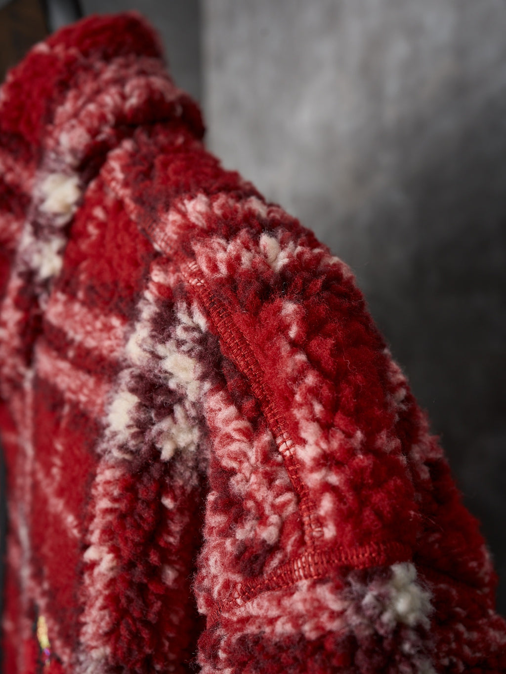 Red plaid jacket sleeve detail with textured fabric and stitched seams