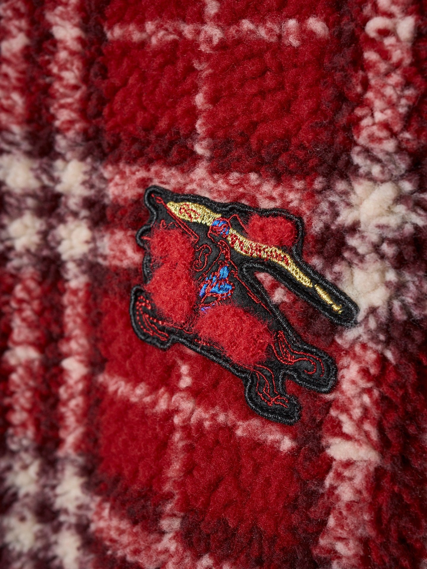Close-up of red plaid jacket with embroidered crest patch