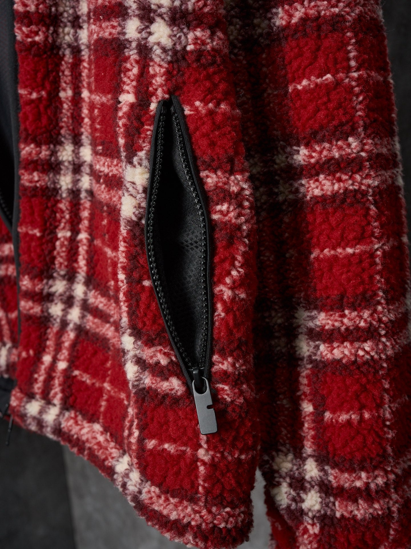 Red plaid jacket front with black zip and visible pocket seam