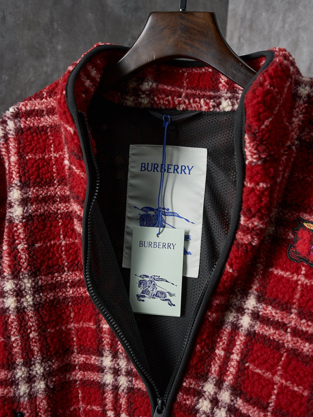 Inside of red plaid Burberry jacket with black lining and neck label