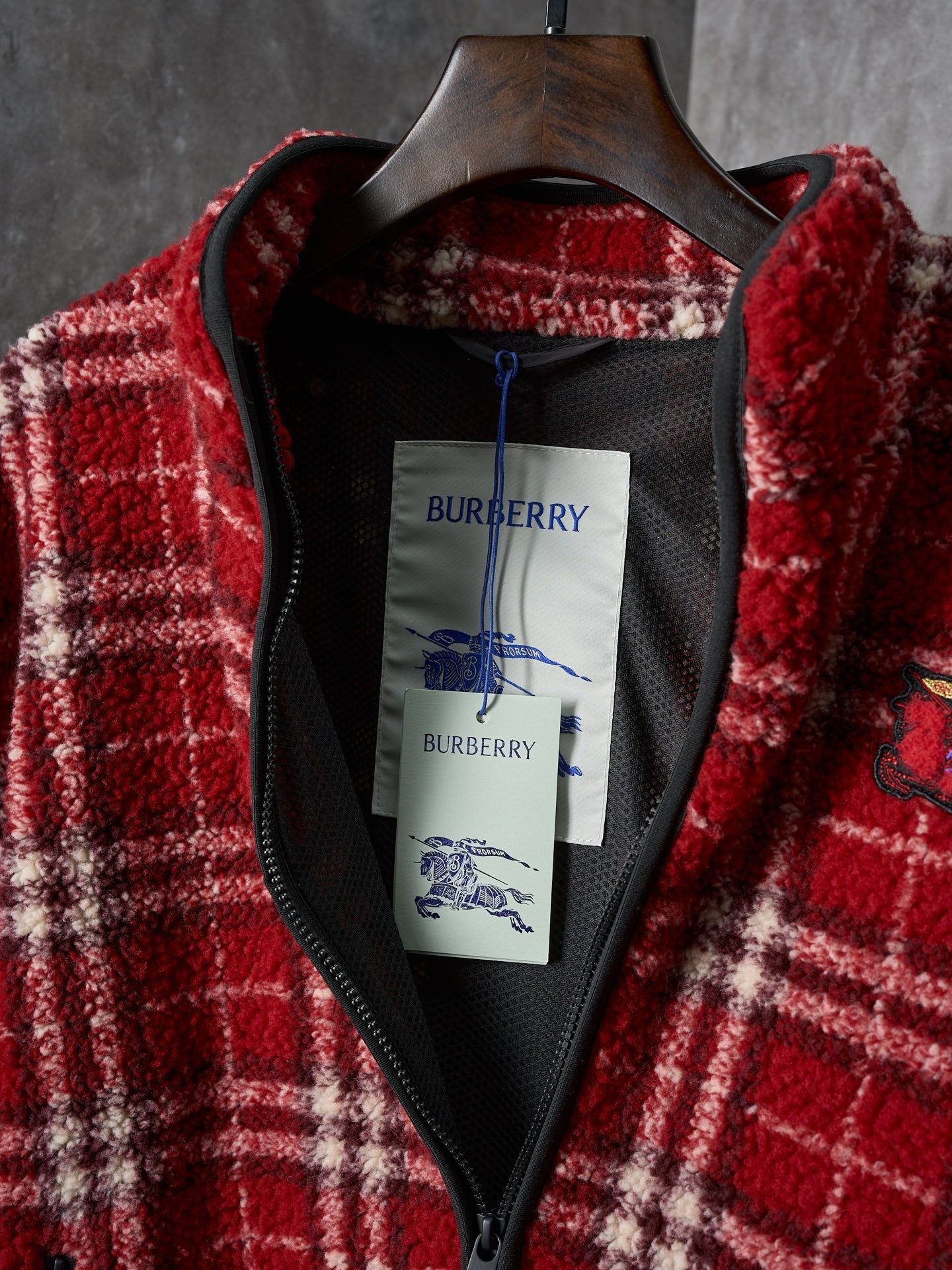Inside of red plaid Burberry jacket with black lining and neck label