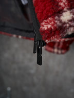 Black zipper placket and drawstring pull on red plaid jacket