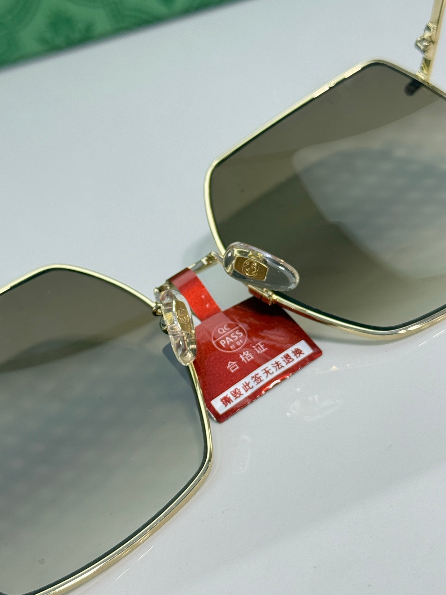 Gucci sunglasses close-up of gold lens edge and red brand tag on temple