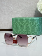 Gucci sunglasses with dark purple lenses and gold frame, bold rectangular style