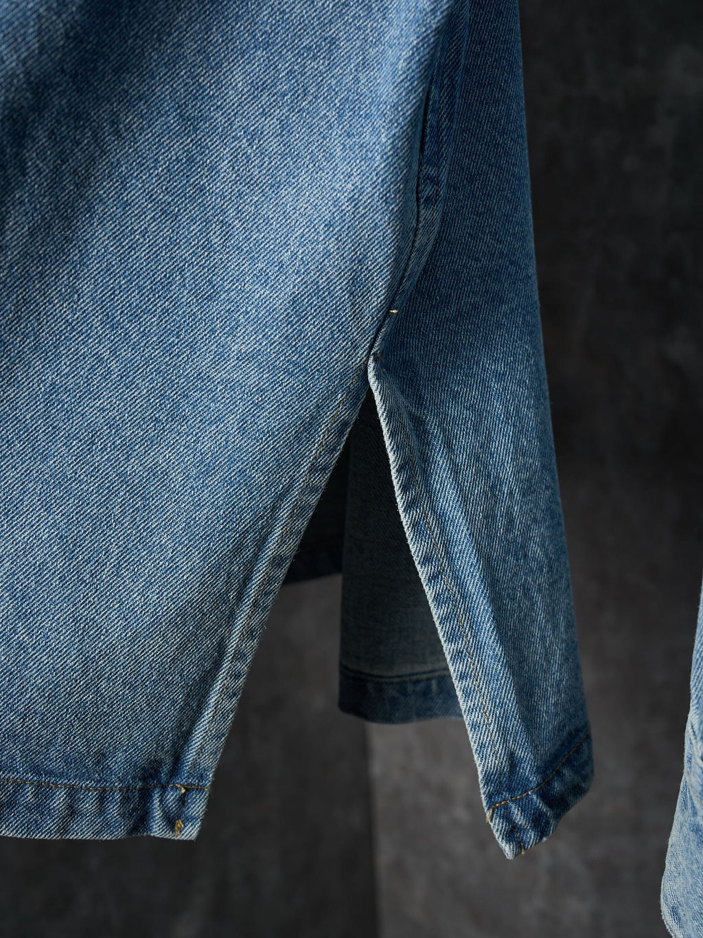 Light blue denim shirt side view with curved hem and sleeve cuff