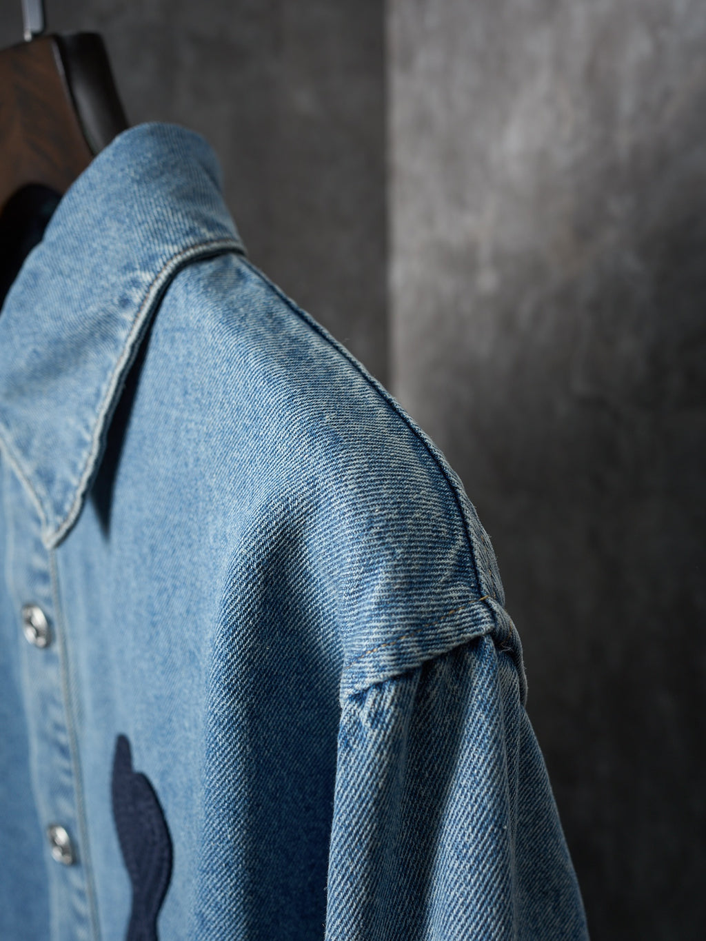 Light blue denim shirt sleeve and shoulder close-up with metal buttons