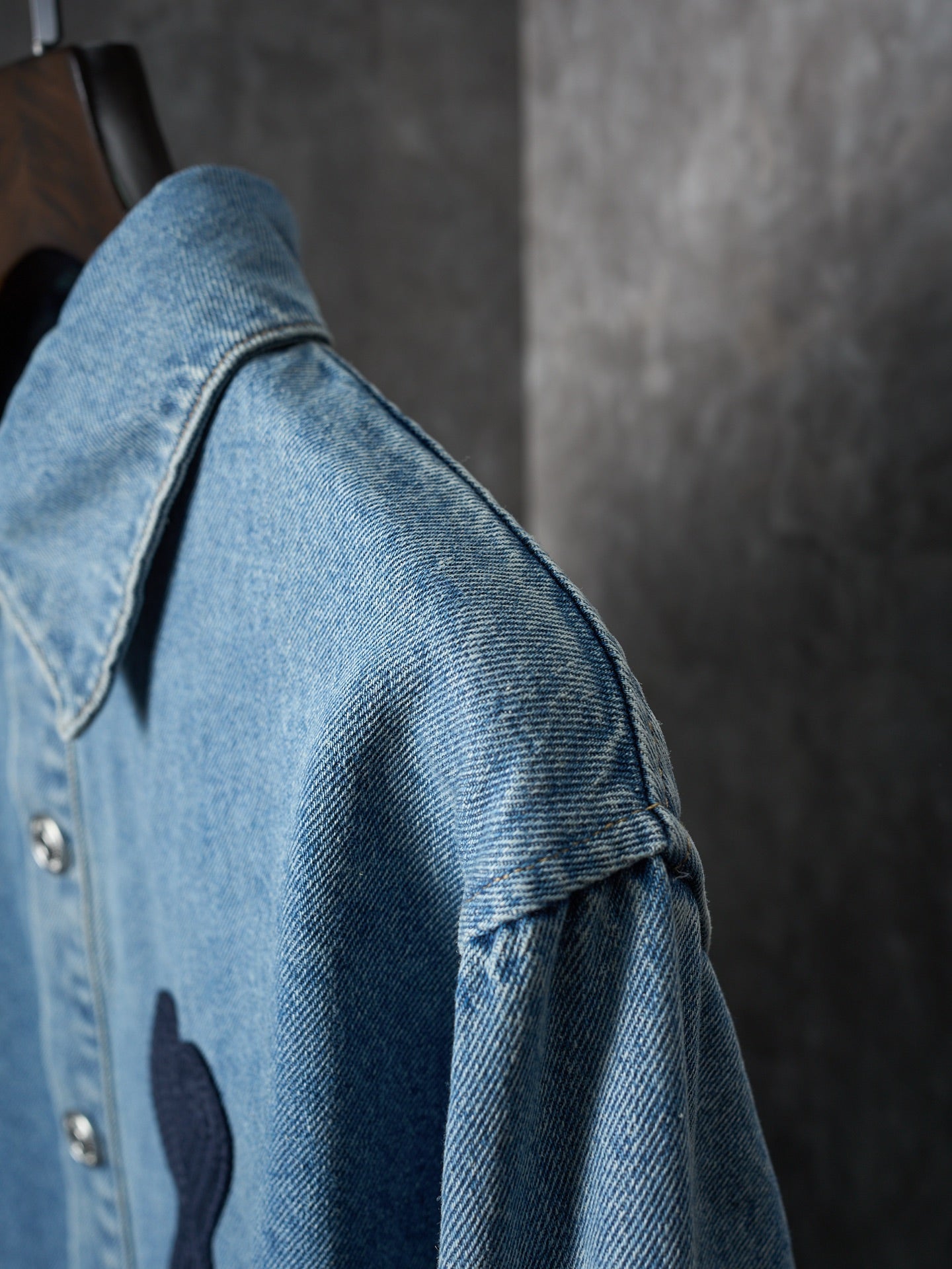 Light blue denim shirt sleeve and shoulder close-up with metal buttons