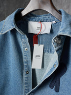 Denim shirt neckline and chest close-up with dark heart-and-ribbon patch