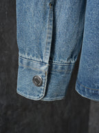 Denim shirt cuff detail with metal snap button at lower edge