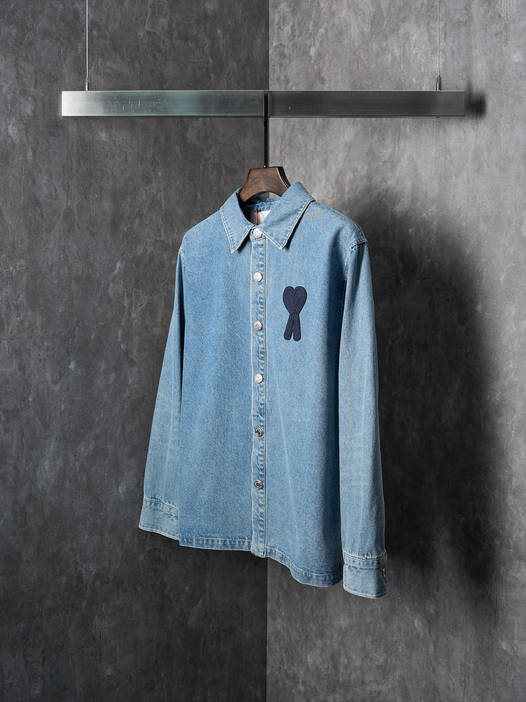 Light blue denim button-up shirt with pointed collar and dark heart-and-ribbon applique