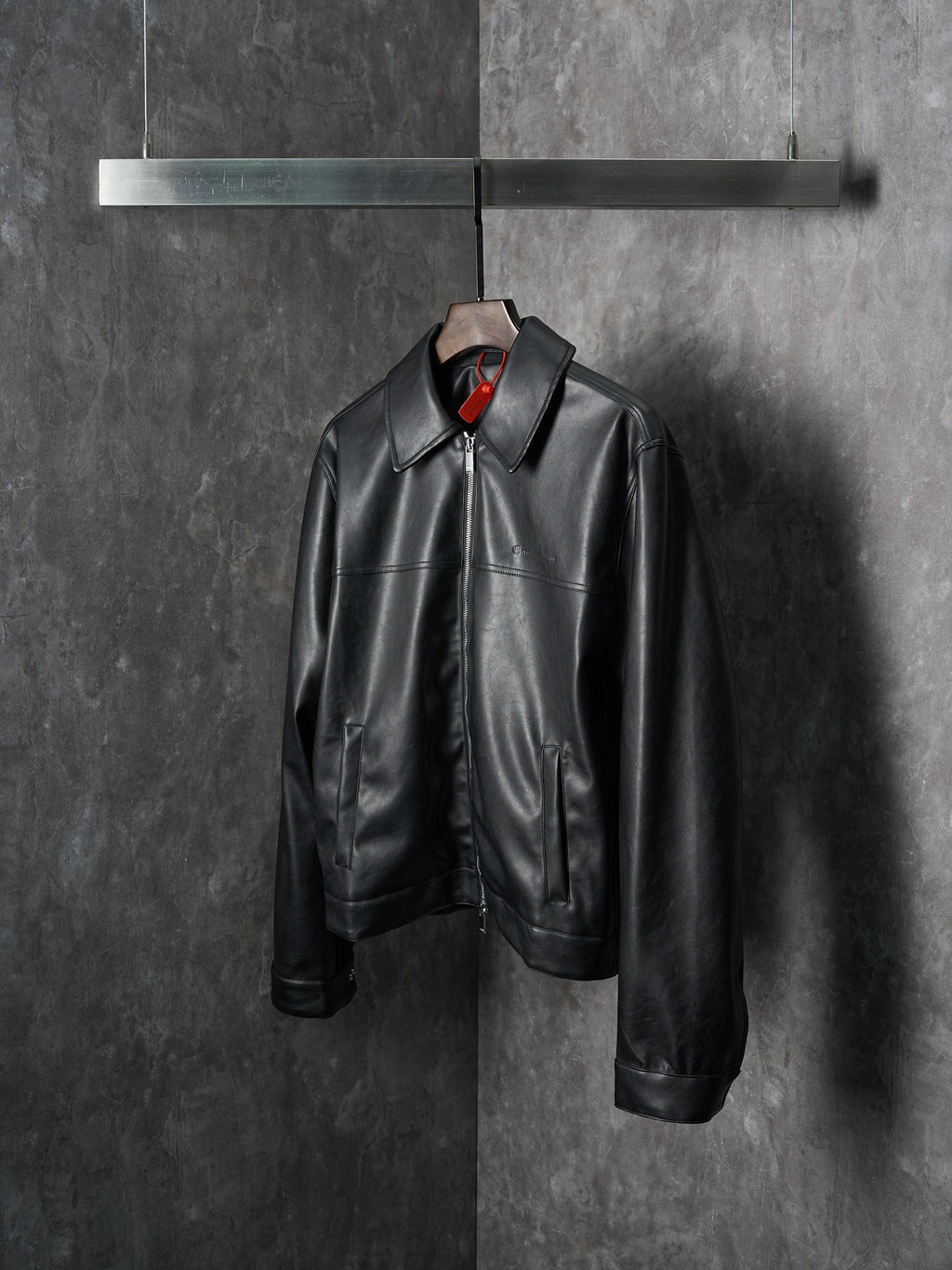 Dior black leather jacket with stand collar and front zipper closure, hanging
