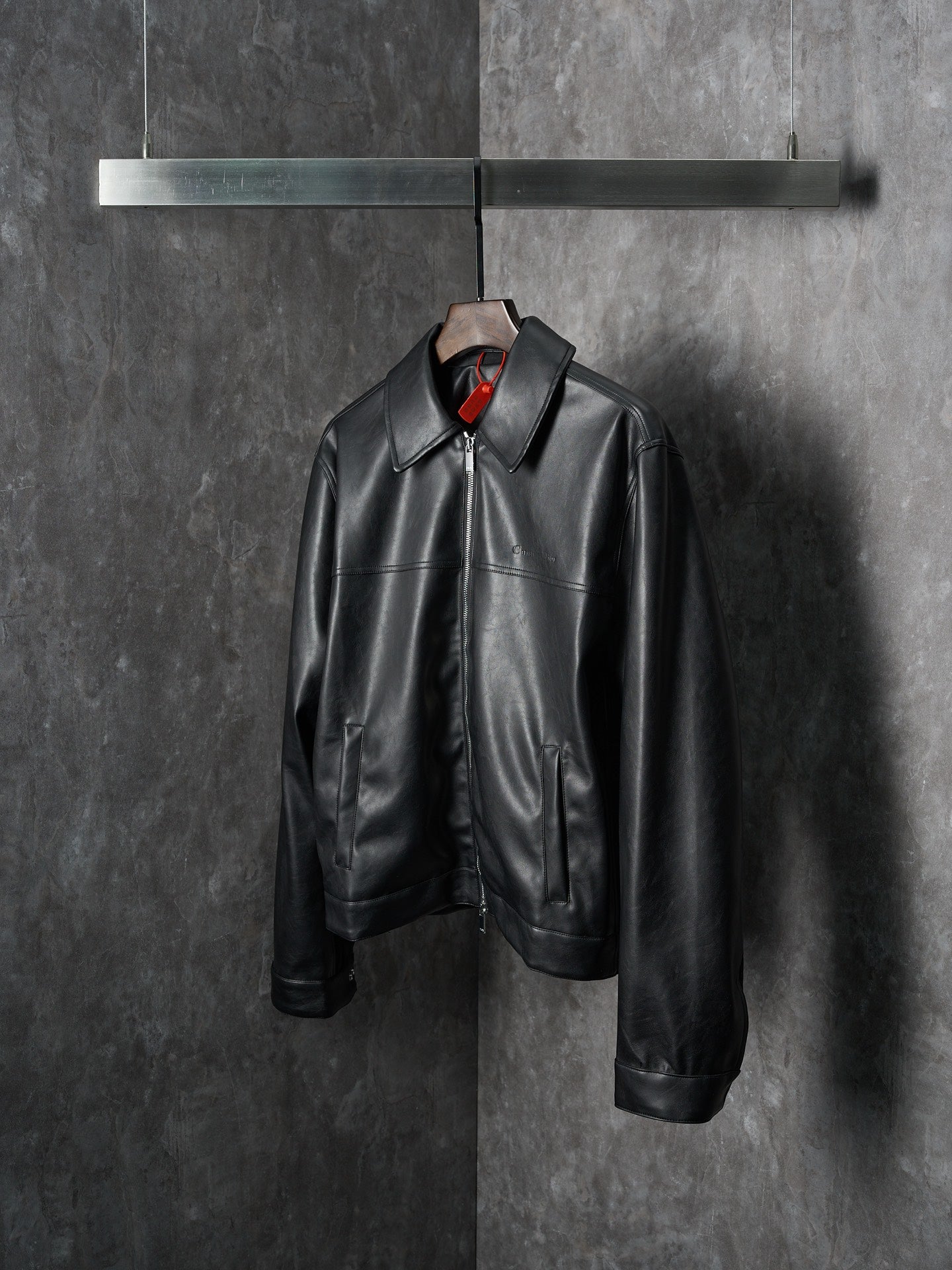 Dior black leather jacket with stand collar and front zipper closure, hanging