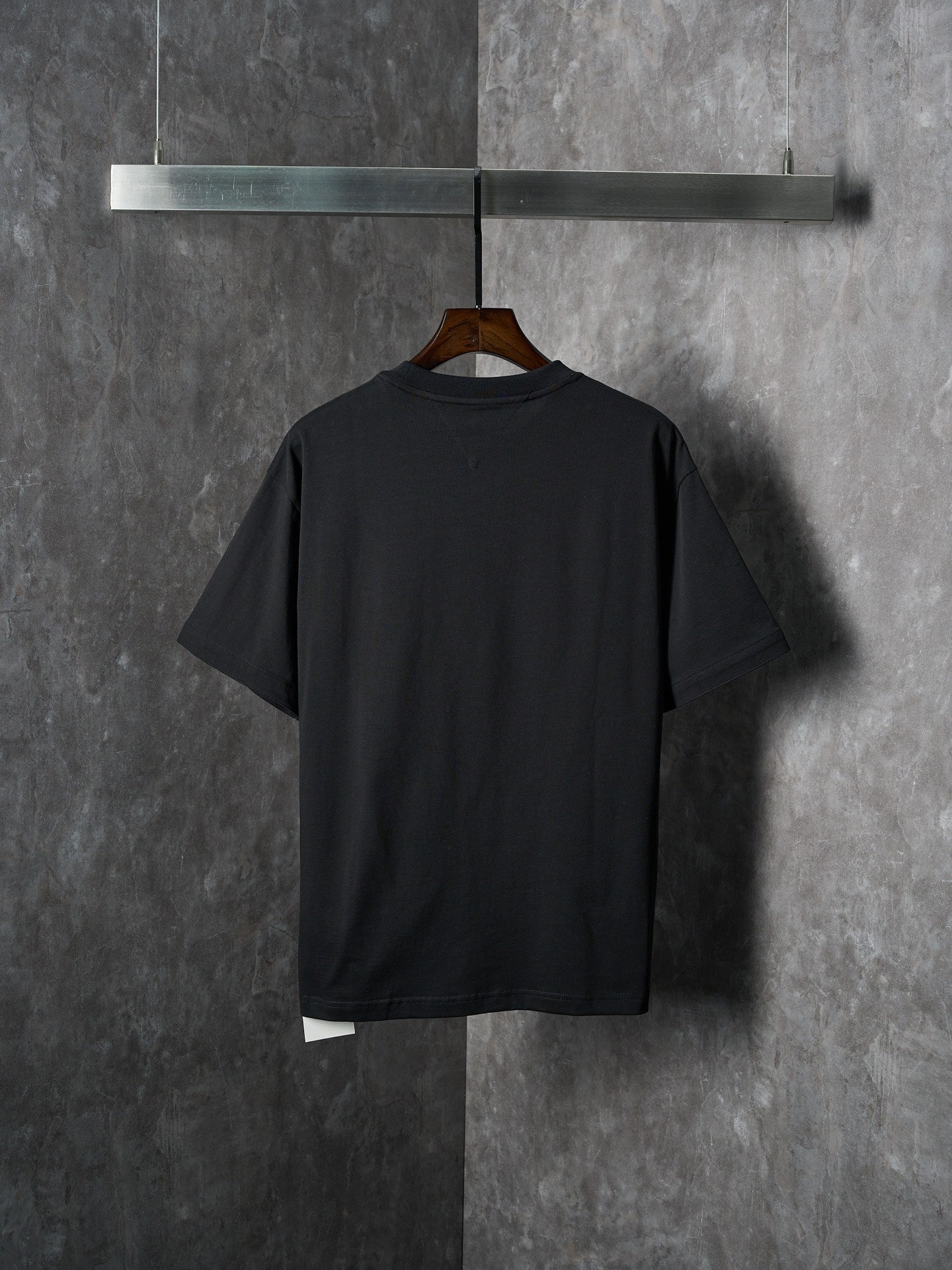 Black short-sleeve T-shirt, back view with curved hem and underlayer at bottom