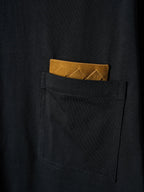 Black T-shirt pocket with tucked yellow accent card visible
