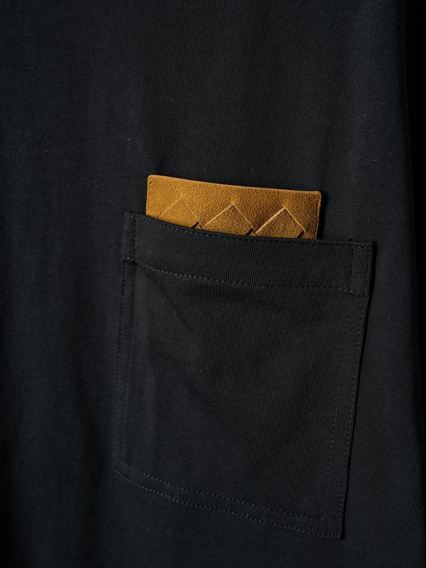 Black T-shirt pocket with tucked yellow accent card visible