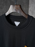 Black crewneck T-shirt with inner neckline label, hung on a wooden hanger