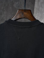 Black T-shirt neckline and back collar seam, hung on a wooden hanger