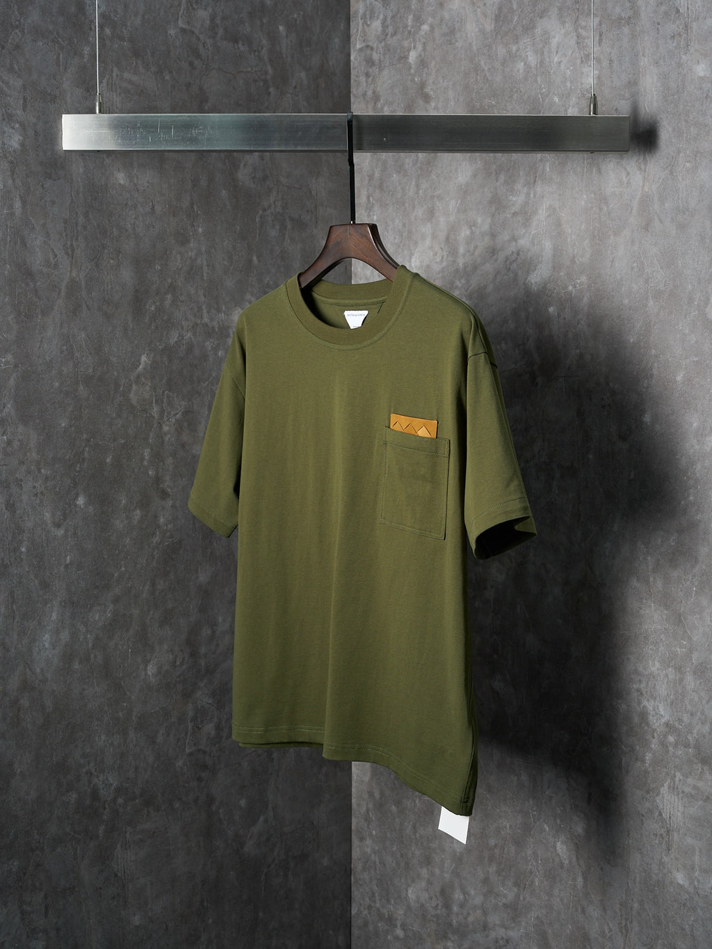 Olive green short-sleeve T-shirt with chest pocket and orange logo patch