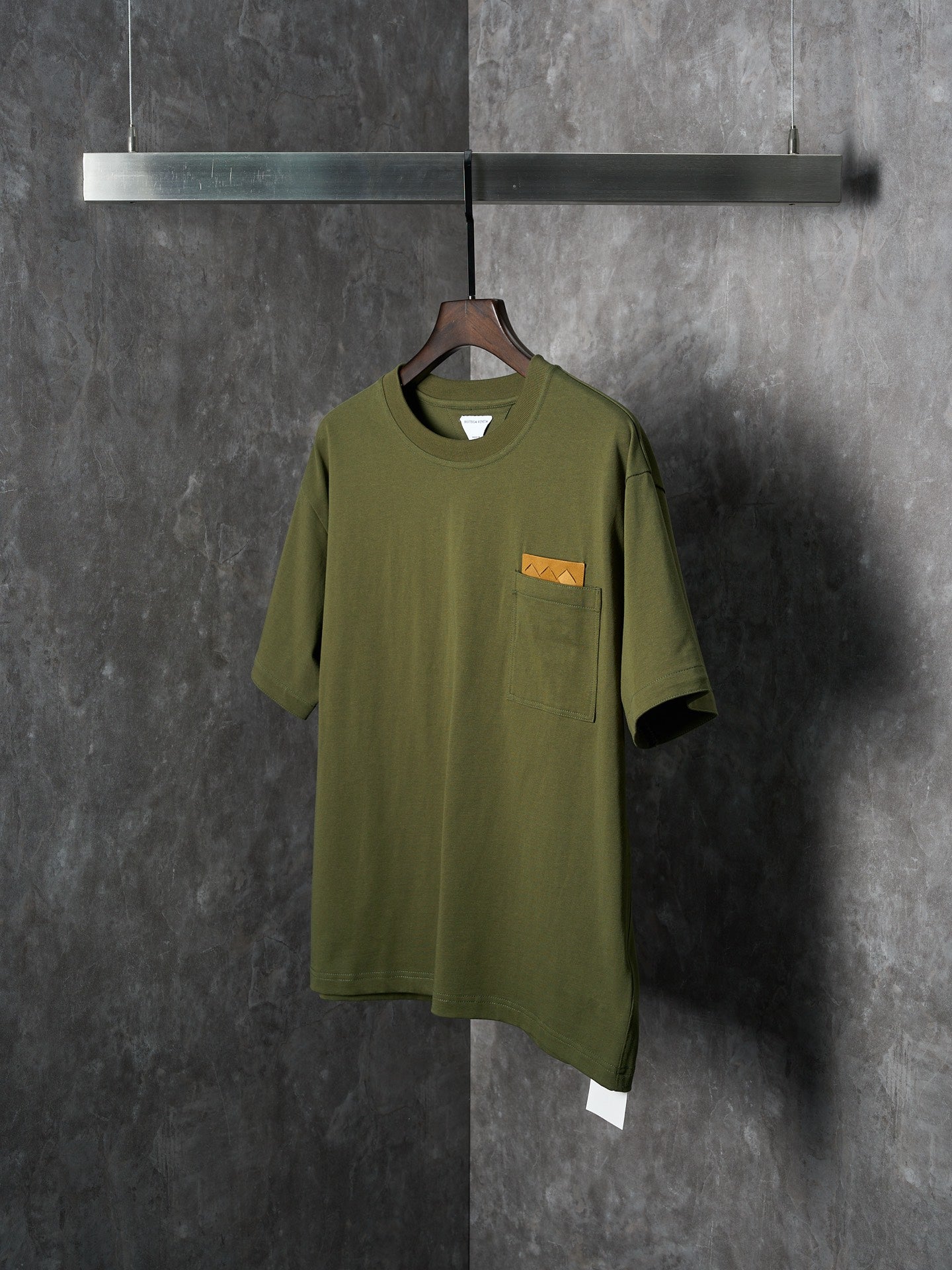 Olive green short-sleeve T-shirt with chest pocket and orange logo patch