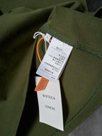 Olive green T-shirt with hanging retail tags and orange brand tag