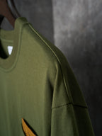 Olive green short-sleeve T-shirt with side seam and orange logo patch