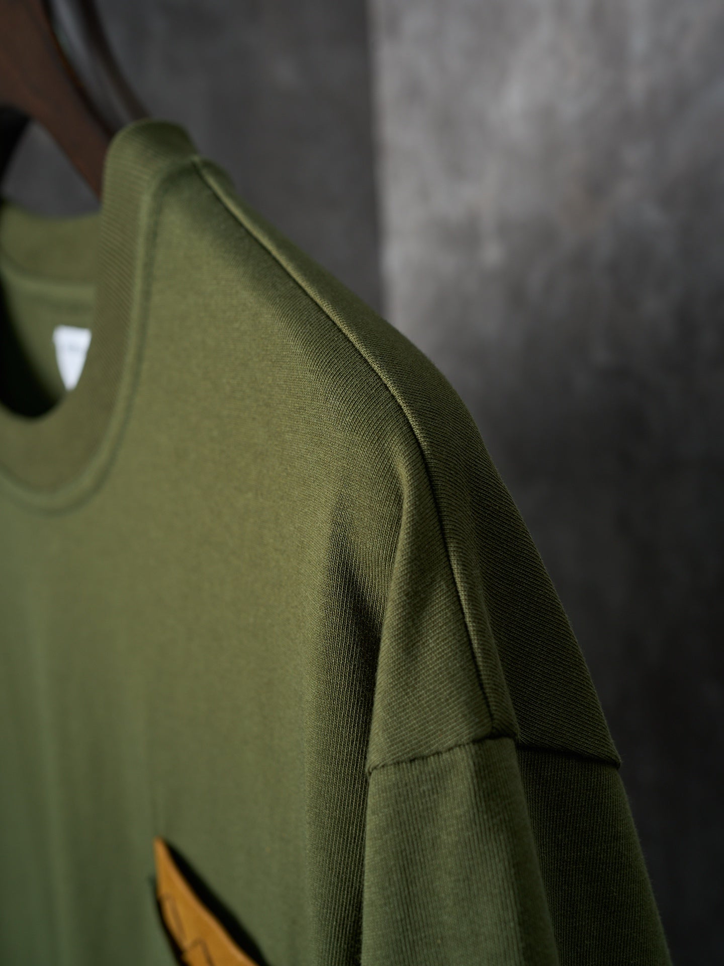 Olive green short-sleeve T-shirt with side seam and orange logo patch