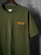Olive green T-shirt with front chest pocket and orange logo tag