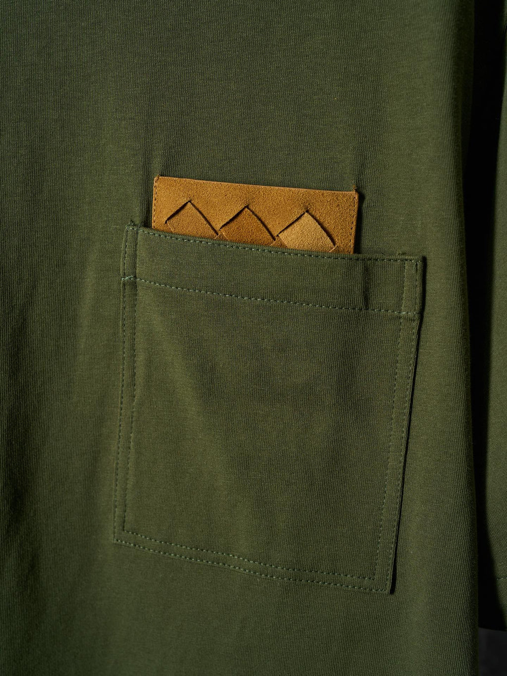 Olive green T-shirt with visible chest pocket and orange logo patch