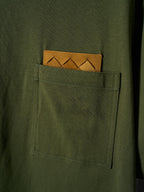 Olive green T-shirt with visible chest pocket and orange logo patch