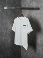 Off-white T-shirt with chest pocket and brown embroidered patch, front view on hanger