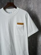 Off-white T-shirt with front chest pocket and brown embroidered patch detail