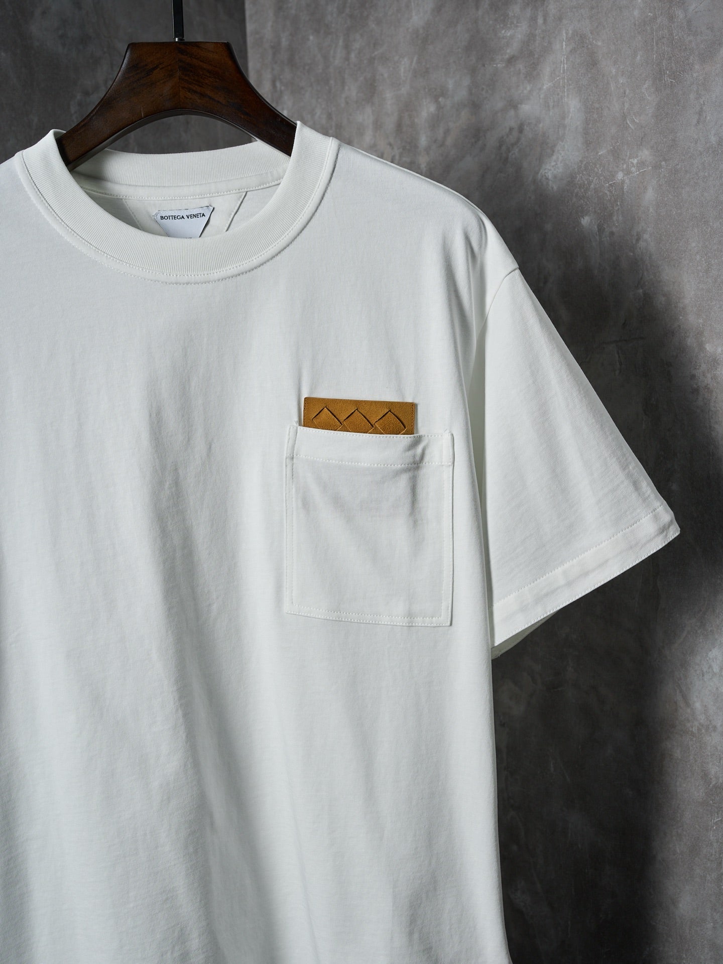Off-white T-shirt with front chest pocket and brown embroidered patch detail