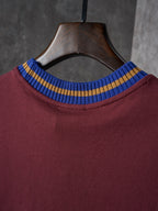 Burgundy T-shirt neckline close-up with blue and yellow striped ribbed collar