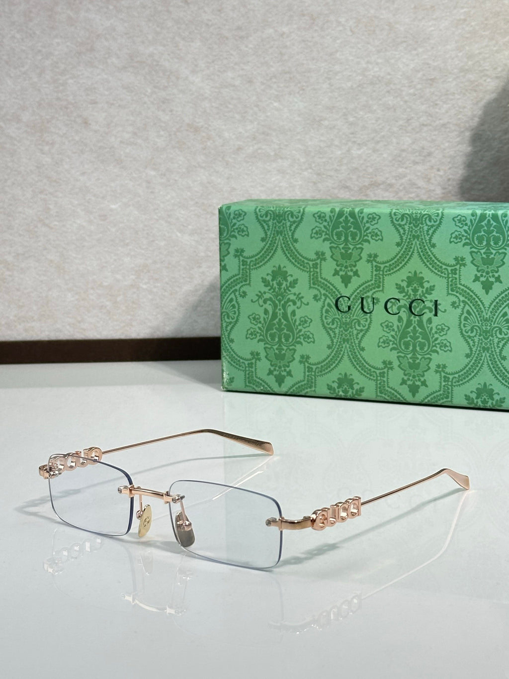 Gucci rectangular eyeglasses with clear lenses, gold-tone rim, and beaded temples