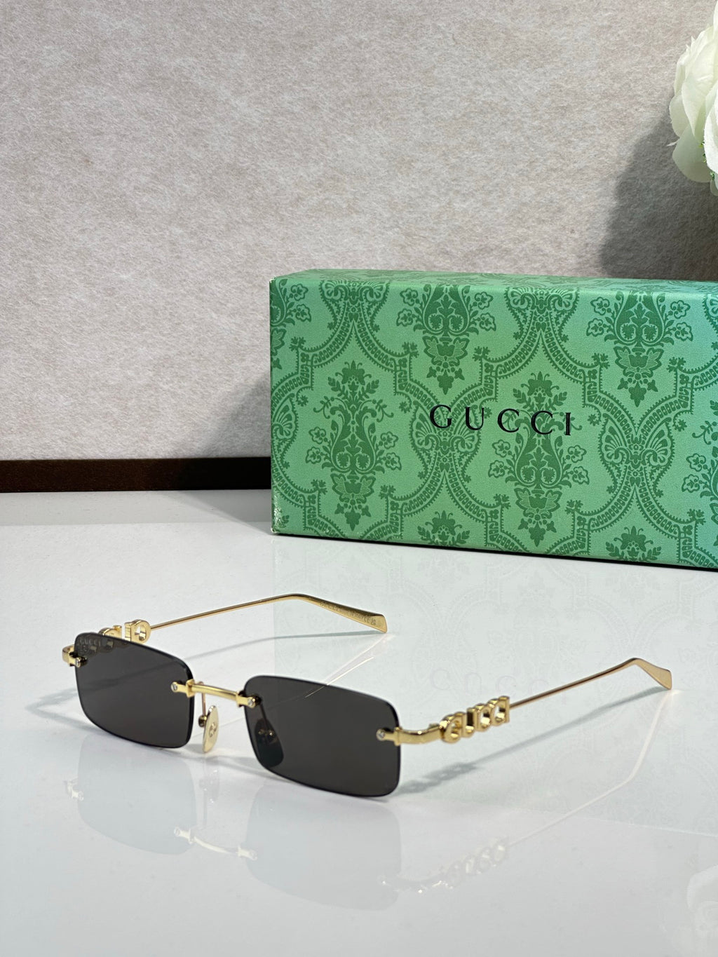 Gucci rectangular sunglasses with dark lenses, gold-tone frame, and beaded temple detail