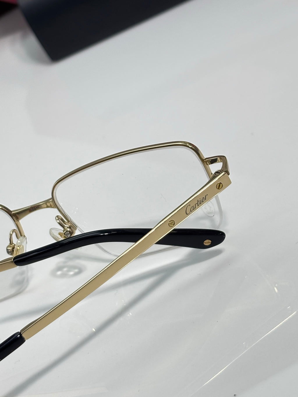 Cartier eyeglasses with gold-tone frame, clear lenses, and black temple arms with logo