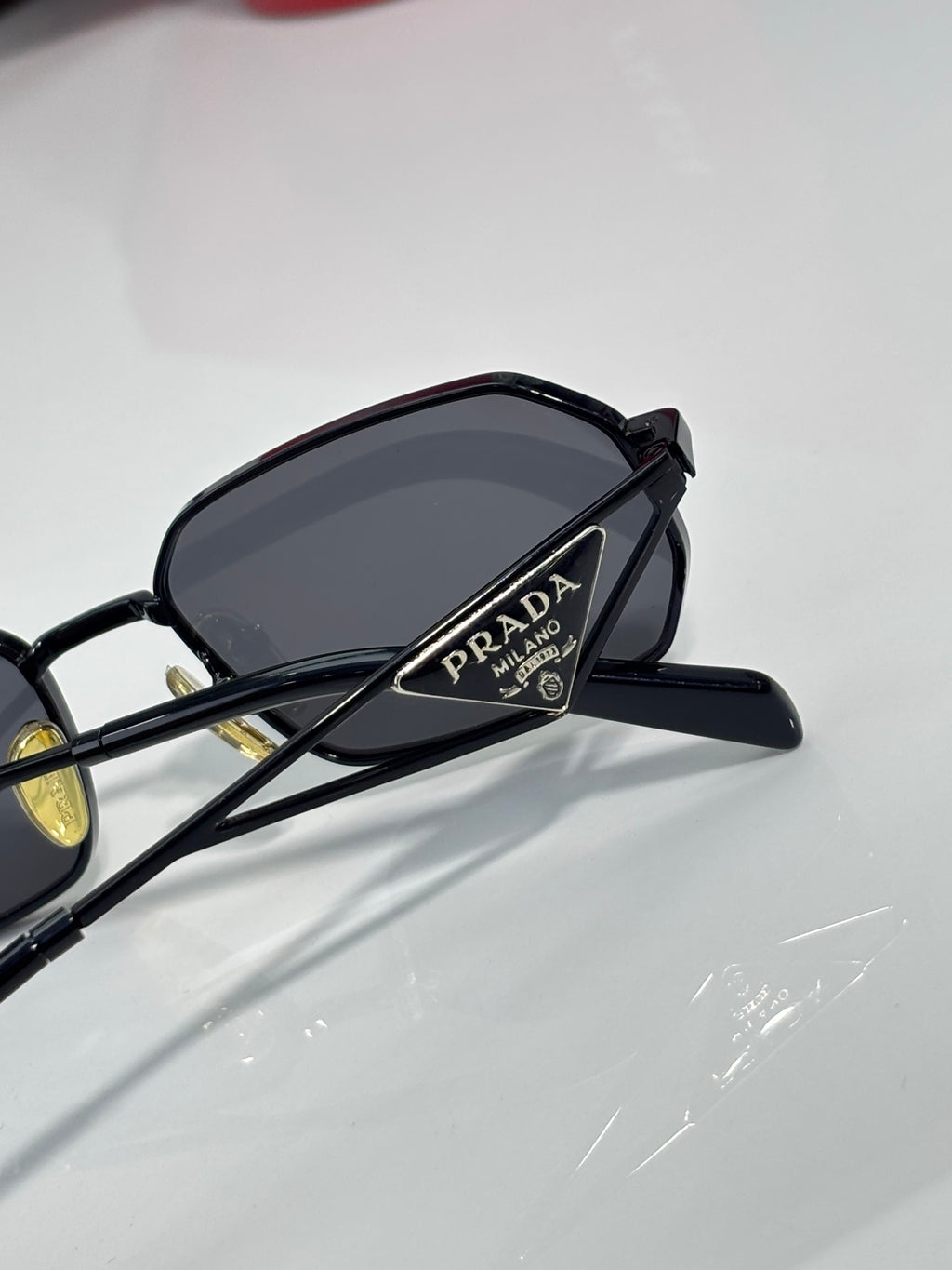Prada sunglasses side view with black frame and dark lens, showing logo on temple.