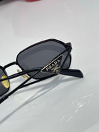 Prada sunglasses side view with black frame and dark lens, showing logo on temple.