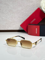 Prada sunglasses with gold frame and brown tinted lenses, with a red logo case.