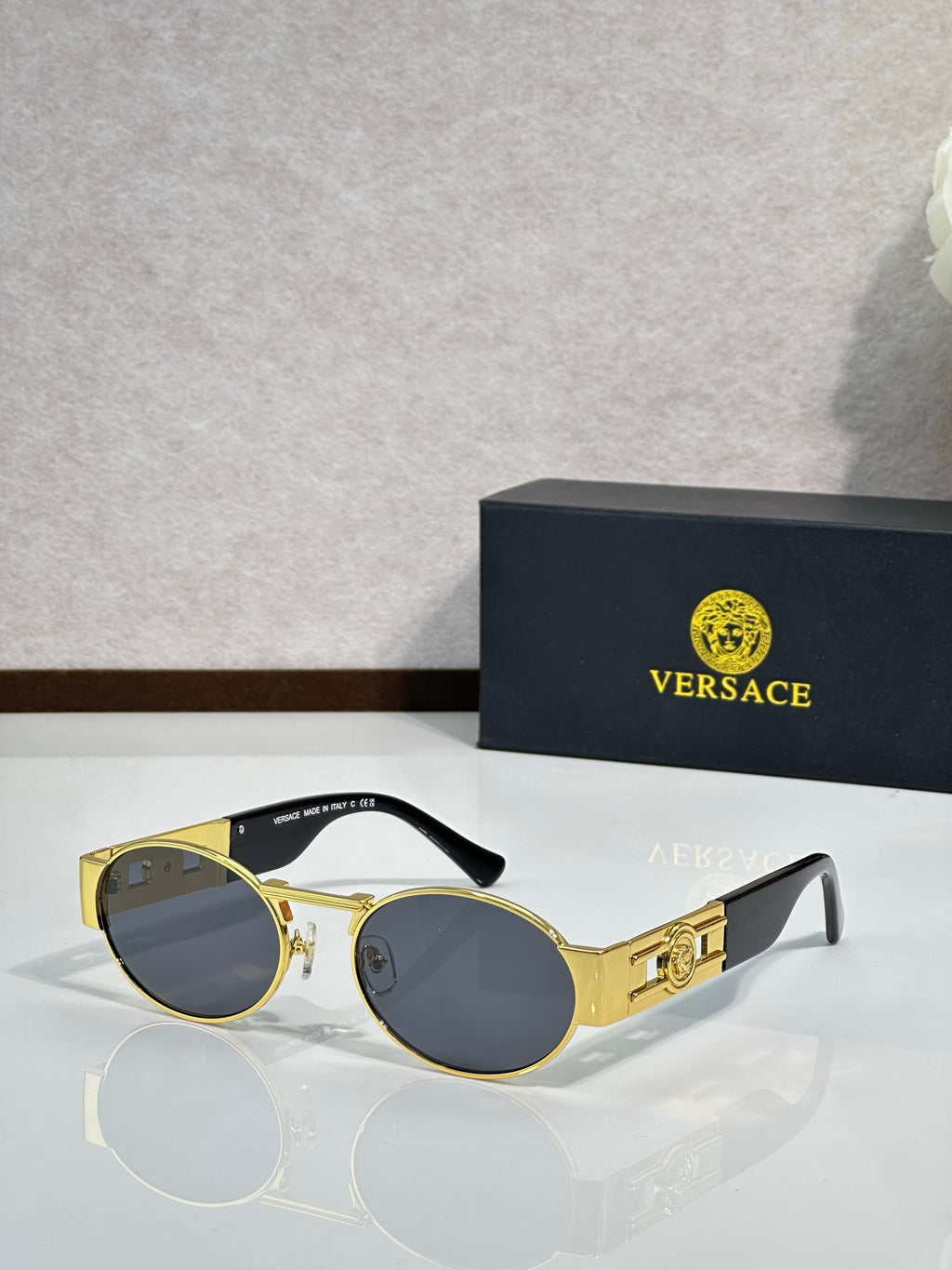 Versace round sunglasses with gold frame and dark lenses, black temple tips
