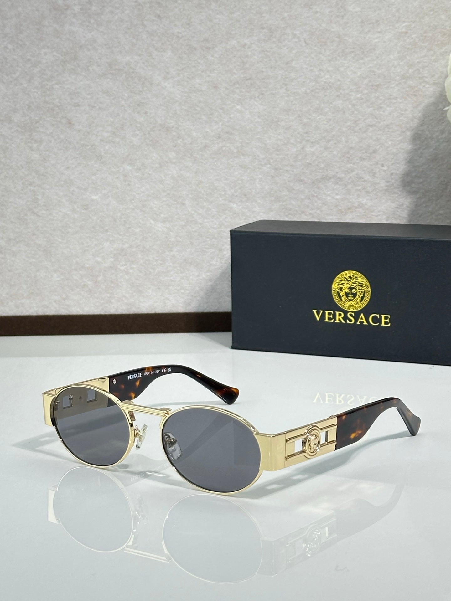 Versace round sunglasses with gold frame and dark lenses, black temple tips