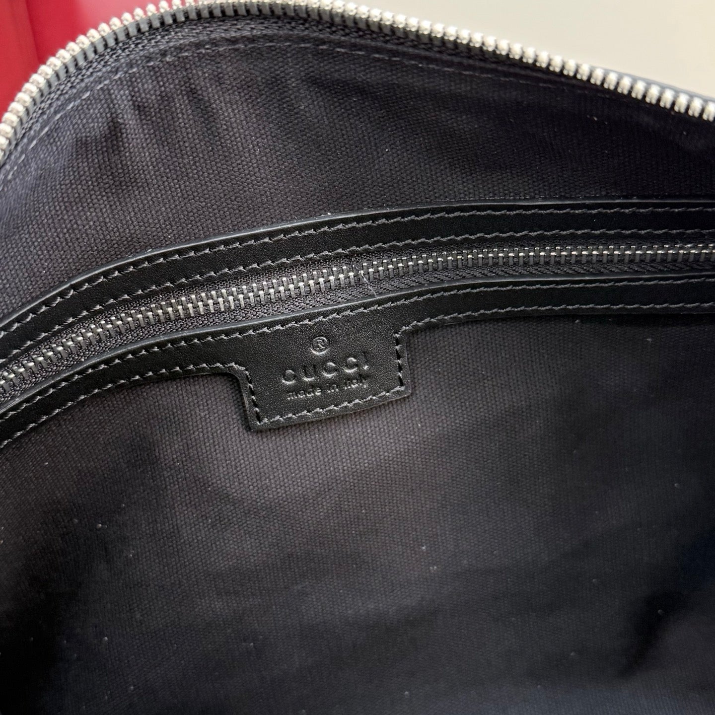 Handbag interior close-up showing small Gucci leather label near zipper