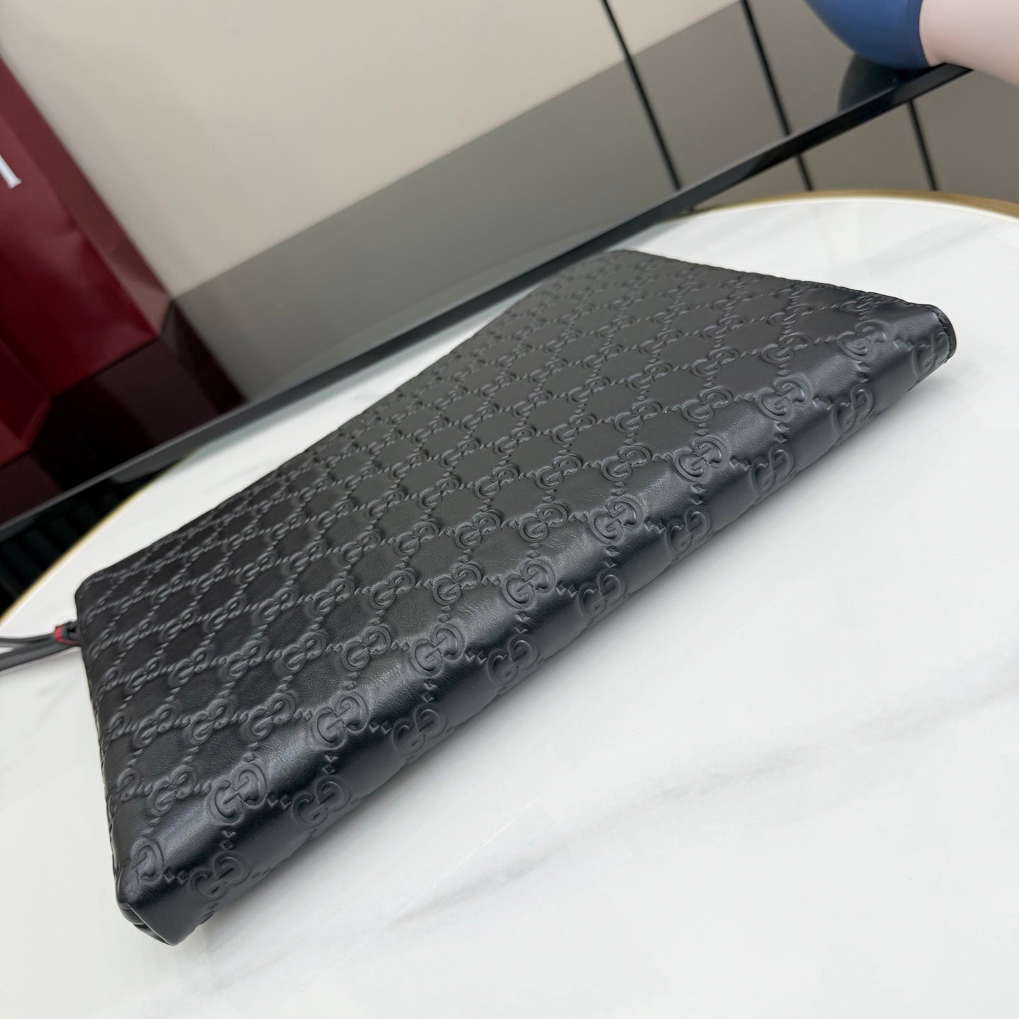 Gucci GG monogram clutch pouch bag, dark with zip top and extended wrist strap.